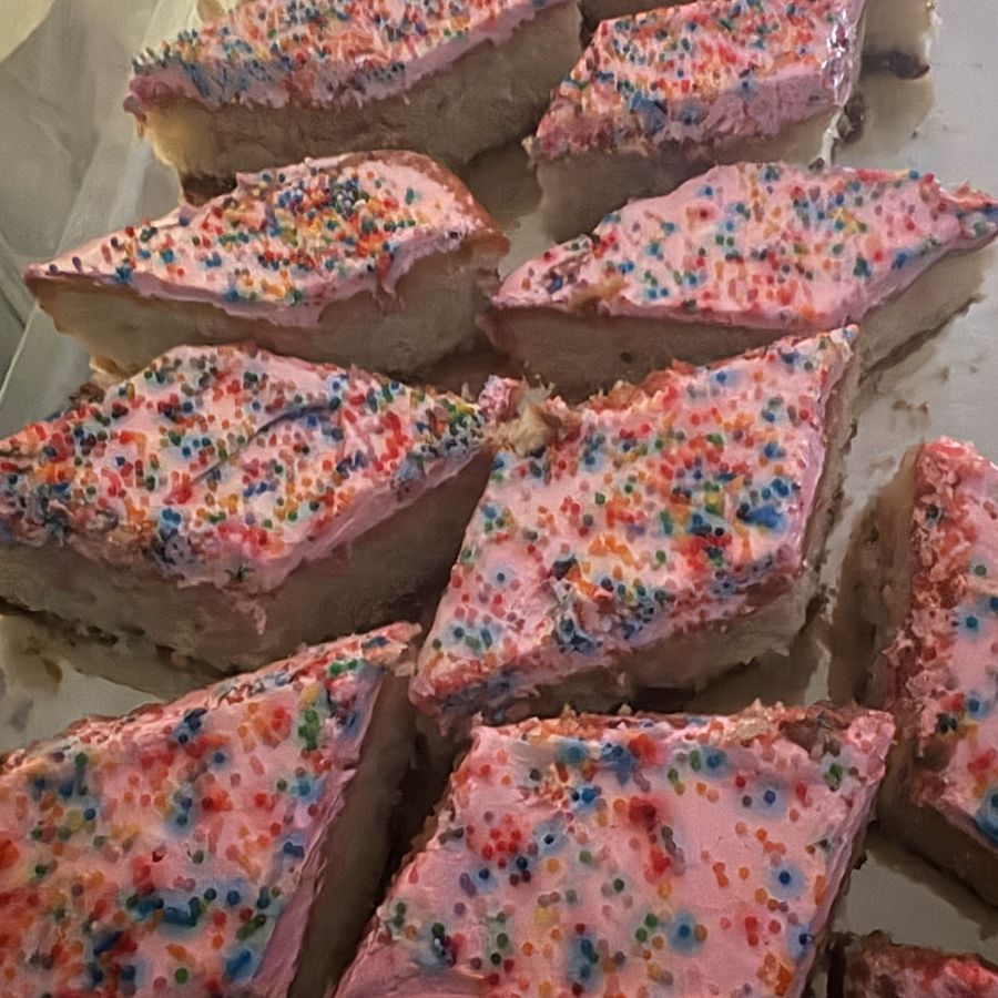 Rebanadas de pastel con betún rosado y chispas en la vitrina